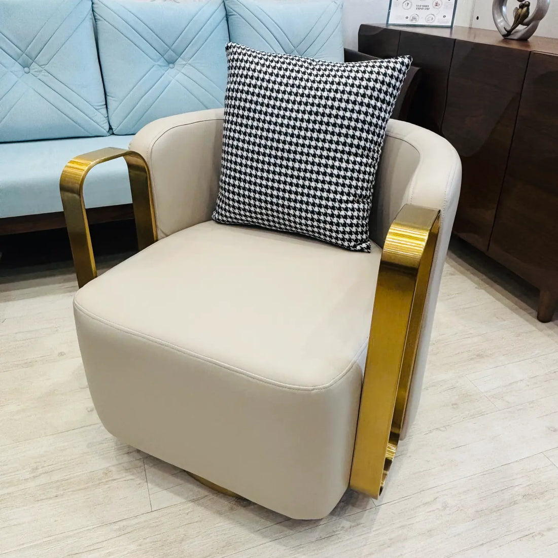 Beige armchair with gold accents and a black and white checkered pillow in a room setting.